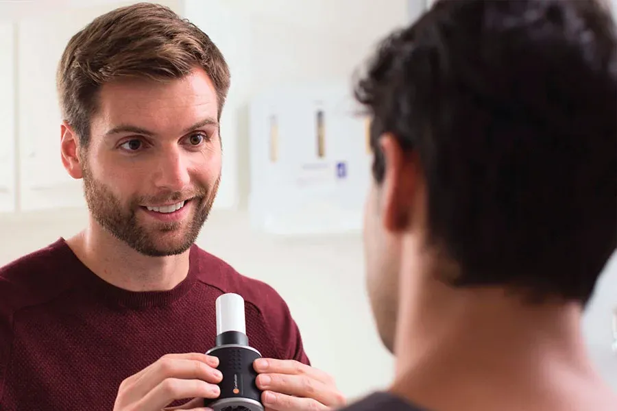 Patient blowing into a spirometer to measure lung function
