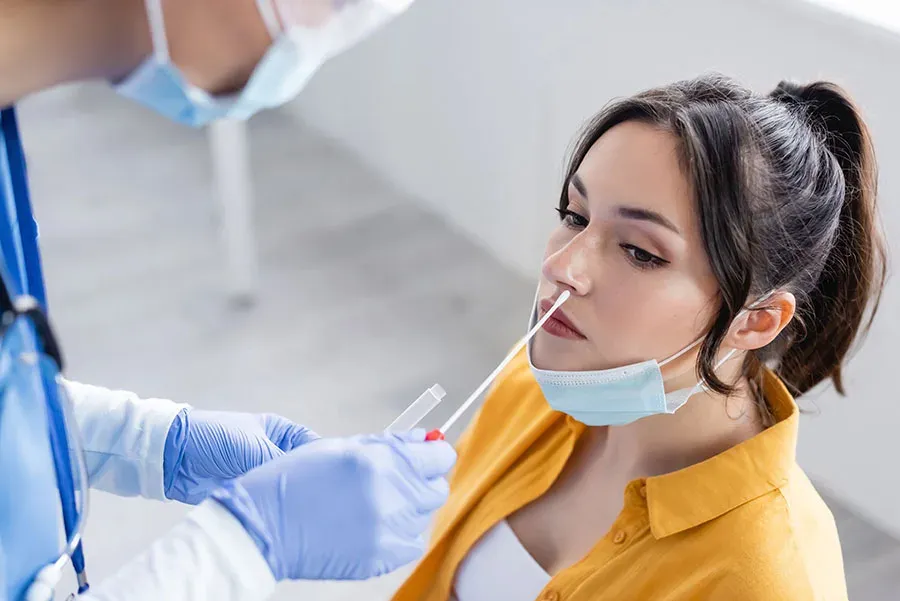 Nurse collecting a nasal swab sample from a patient for COVID-19 testing