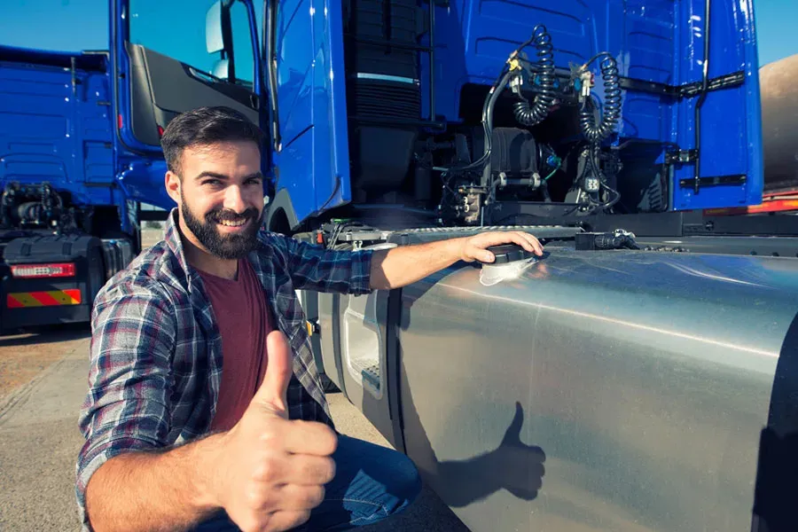 Smiling man giving a thumbs up beside a truck after passing his DOT physical exam