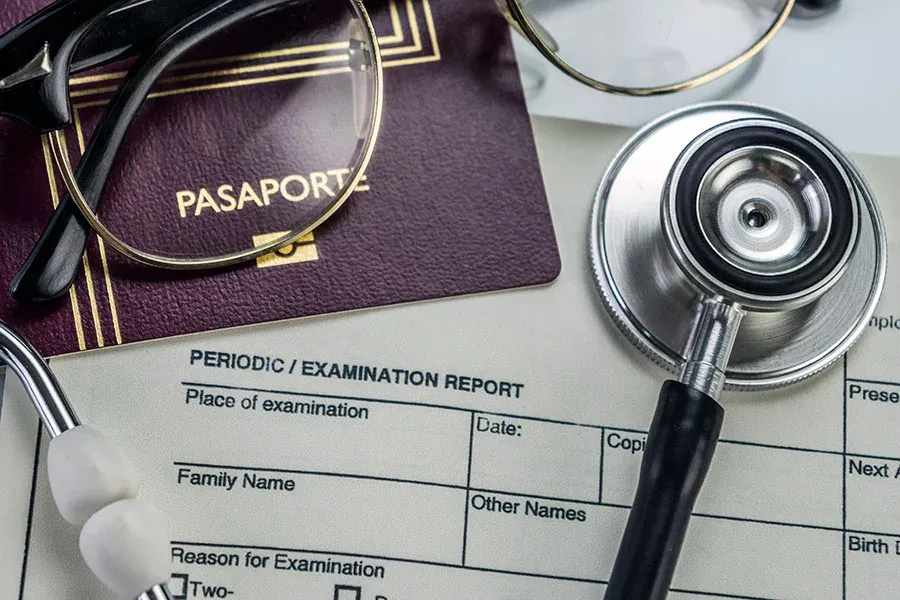 Passport and stethoscope resting on an immigration medical examination form