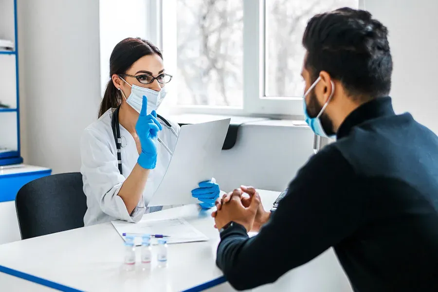 Physician wearing gloves collecting a blood sample from a patient's arm