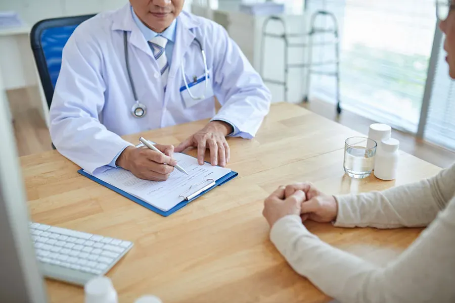 Doctor in a white coat discussing an immigration medical exam with a patient at a desk