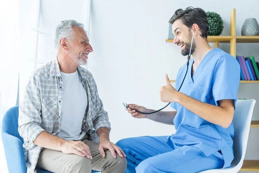 Young doctor gesturing thumb up to an elderly patient